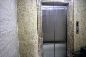 Um elevador com interior metálico e painel de comando no lado direito.