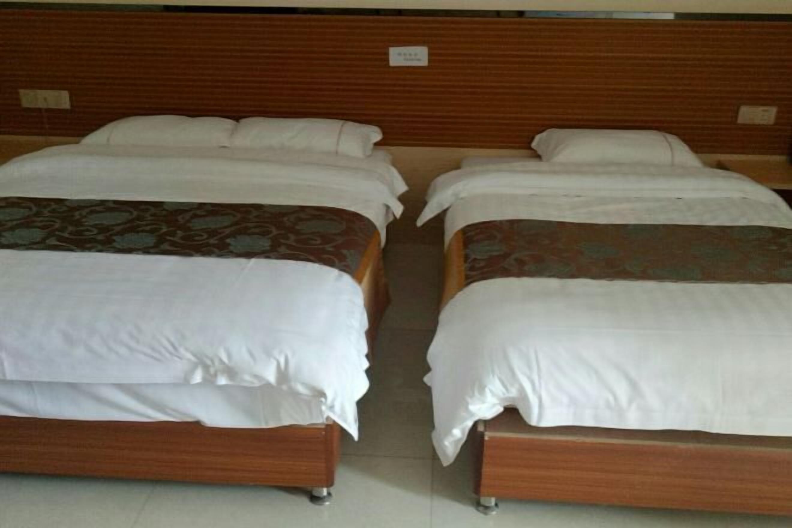 Une chambre d’hôtel avec deux lits simples, chacun doté d’un cadre en bois et de draps blancs.