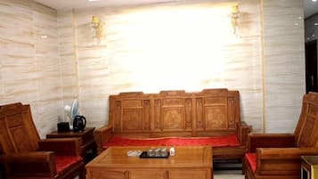 Habitación con sofá de madera, una mesita de centro y una manta roja.