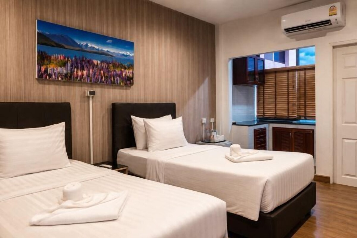 Habitació d'hotel amb dos llits, un quadre a la paret i una zona de cuina compacta.