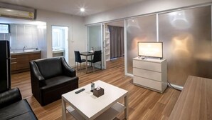 A modern living room with a sofa, a coffee table, a TV, and a sliding door leading to a balcony. - Crystal Resort (Nakhon Ratchasima)