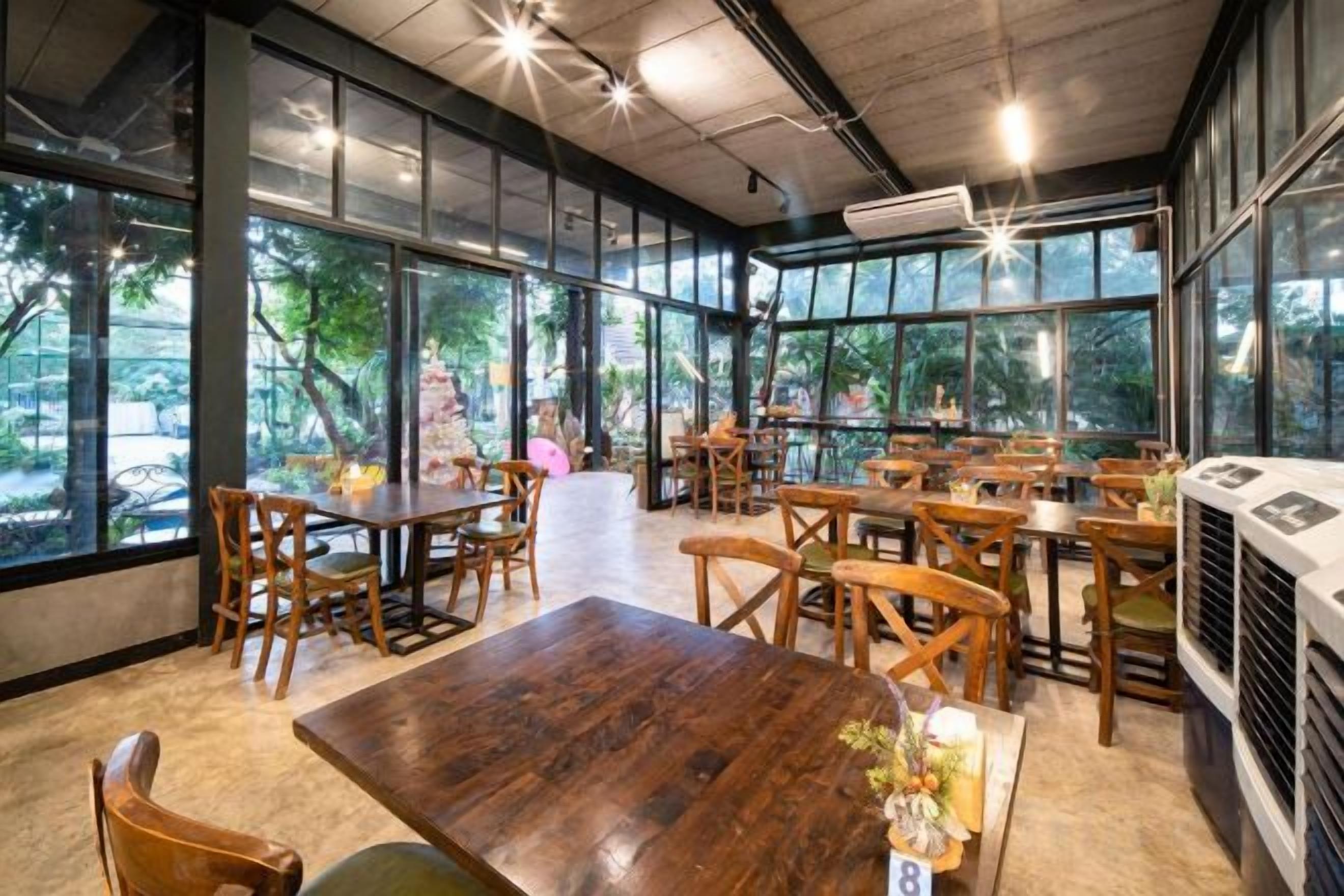 An indoor dining area with tables and chairs, large windows, and a view of the outdoors.