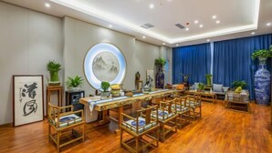 A spacious room with a long wooden dining table, several wooden chairs, and a blue curtain. - Sopley li zhi Hotel (Zhengzhou)