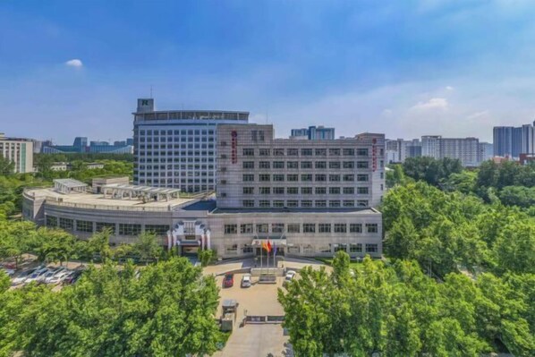 A large, multi-story building with a central courtyard and flagpoles. - Sopley li zhi Hotel (Zhengzhou)