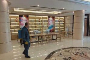 A spacious lobby with a central table and chairs, surrounded by bookshelves and a large abstract painting. - Sopley li zhi Hotel (Zhengzhou)