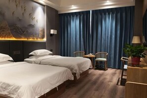 A hotel room with two beds, a small table with chairs, a potted plant, and a wall with a mural. - Sopley li zhi Hotel (Zhengzhou)