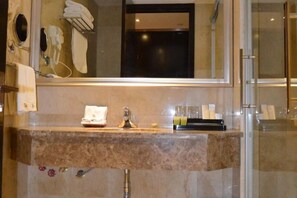 A bathroom with a marble countertop, a mirror, a towel rack, and a glass shower enclosure. - Sopley li zhi Hotel (Zhengzhou)