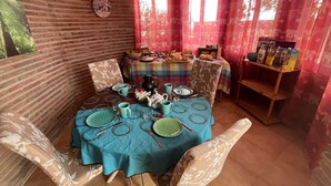 Un coin repas avec un mur en briques, une horloge et une table mise avec des assiettes, des verres et une carafe.