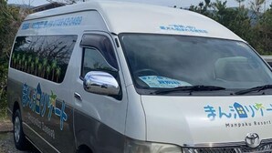 Una camioneta blanca con el logotipo y la información de contacto de Manpaku Resort.