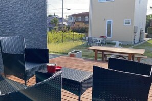 An outdoor patio with wicker furniture, a wooden table, and a red cup. - satsuki (Shirahama)