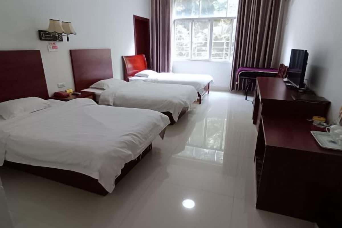 A hotel room with two beds, a desk, a chair, a TV, and a window with curtains.