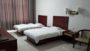 A hotel room with two beds, a desk, a chair, and a nightstand.