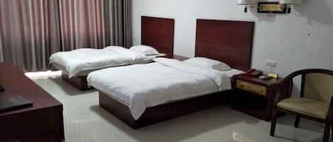 A hotel room with two beds, a desk, a chair, and a nightstand.