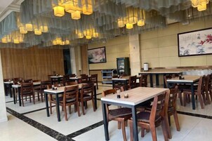Un restaurante con varias mesas y sillas, piso de madera y lámparas colgantes.