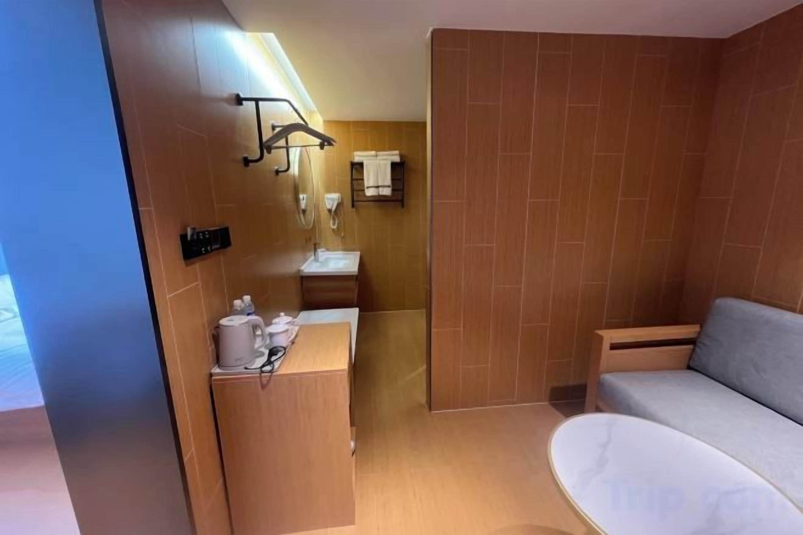 A modern bathroom with a sink, mirror, towel rack, and a shower area.