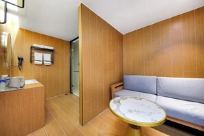 Une chambre d’hôtel moderne avec un mur en bois, un canapé, une petite table ronde et un comptoir de réception.