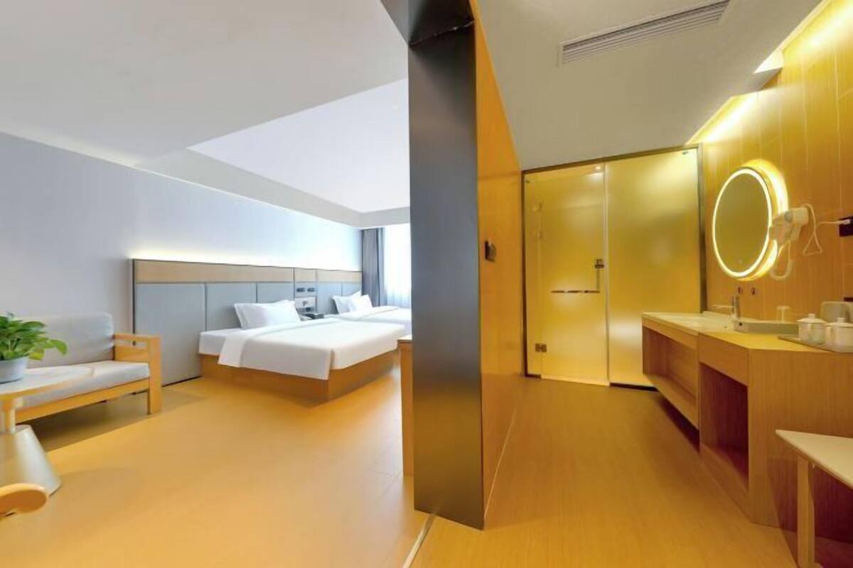 A modern hotel room with a bed, bedside table, and a large mirror with a light.