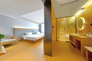 Una habitación de hotel moderna con cama, mesita de noche y un espejo grande con luz.