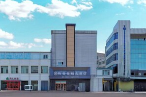 A hotel with a modern facade, a prominent vertical sign, and a parking area in front. - Meixiangchun Collection Hotel (Datong Yungang District) (Datong)