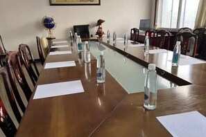Une salle de conférence avec une longue table, des chaises, des bouteilles d’eau et des documents.
