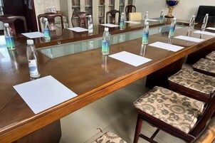 Un salón de conferencias con una larga mesa, sillas, botellas de agua y documentos.