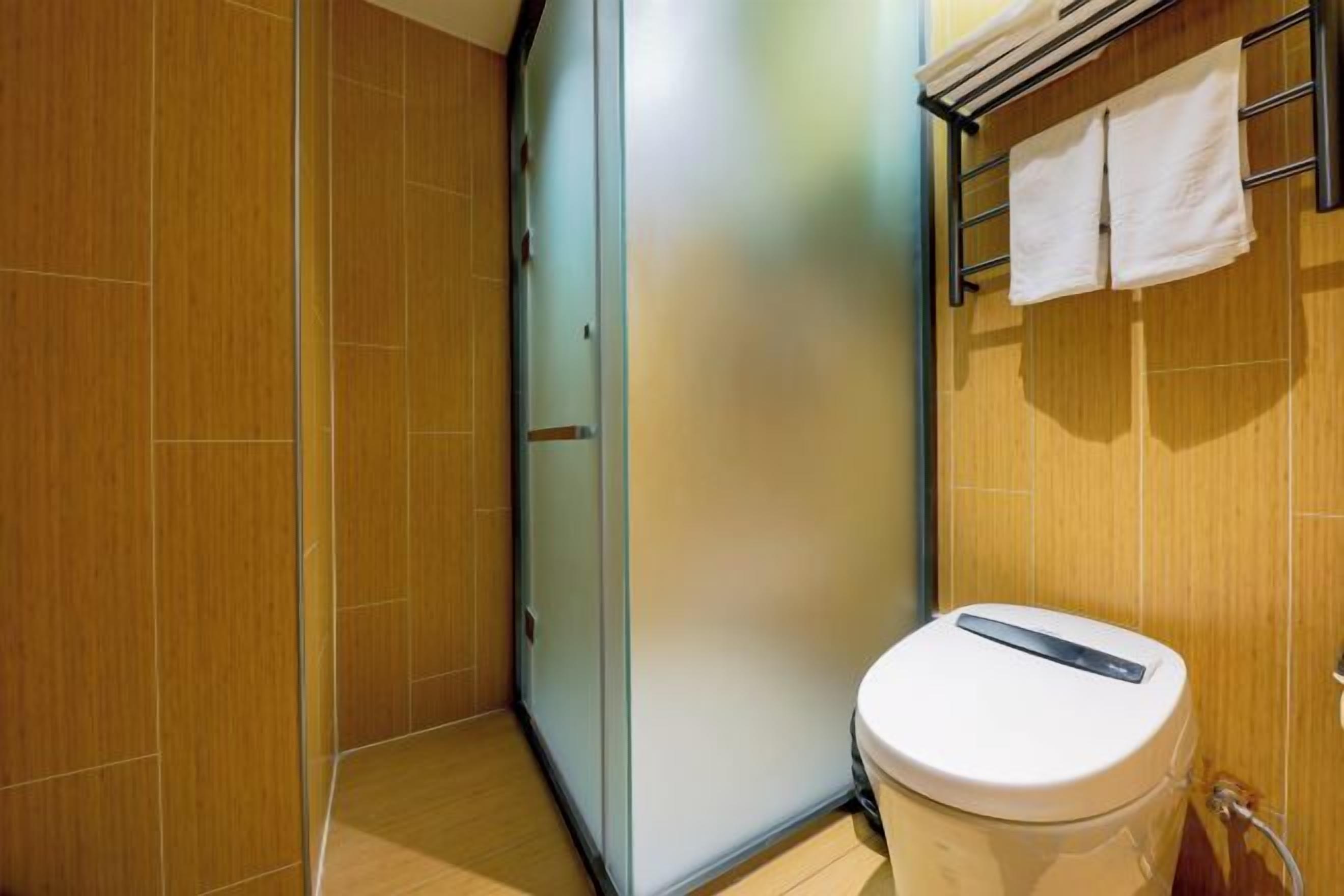 A bathroom with a toilet, a towel rack, and a shower area.