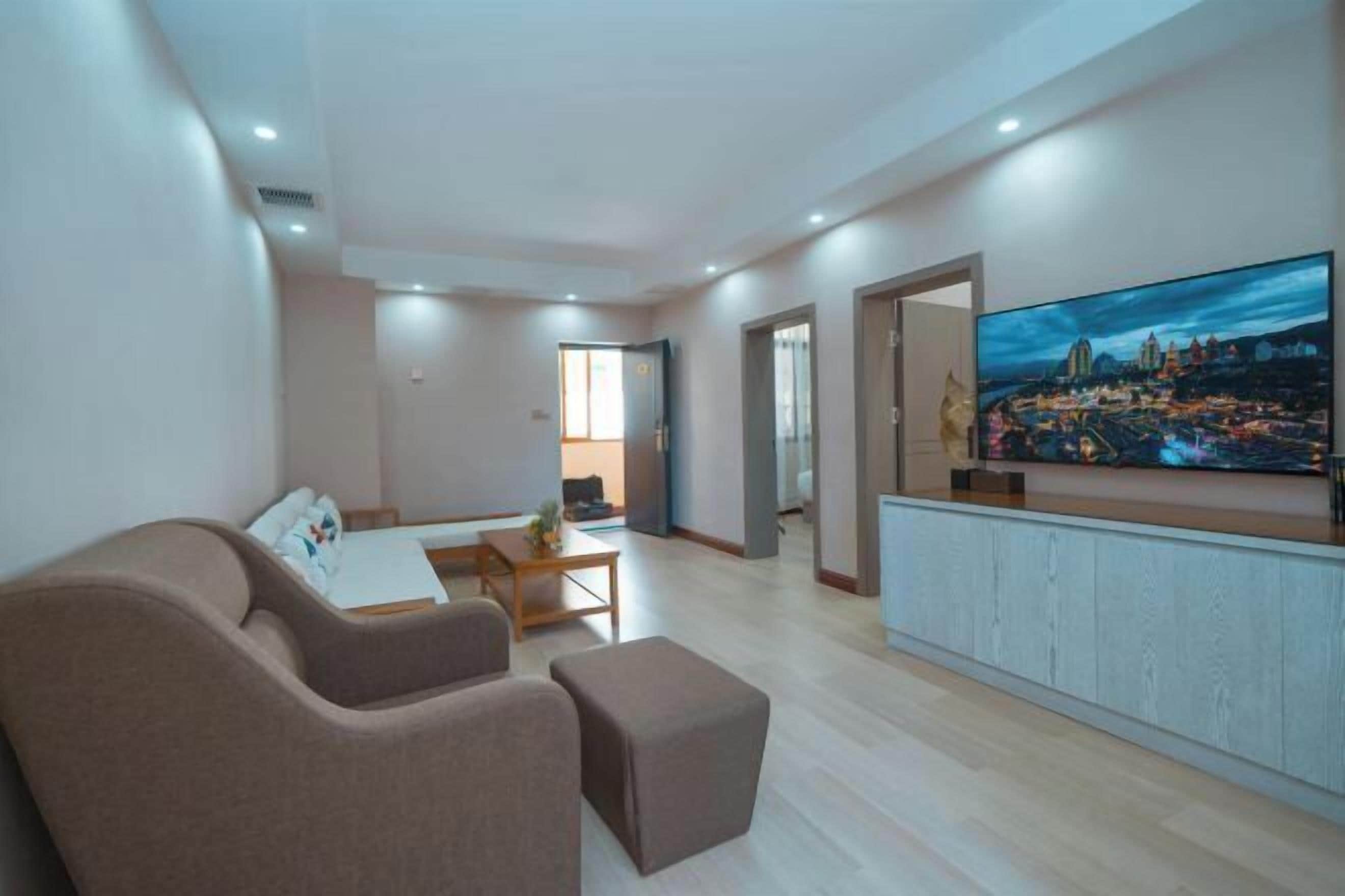 A modern living room with a flat-screen TV, a sofa, a coffee table, and a dining area.