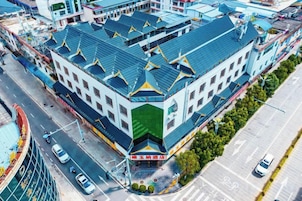 Edifício de vários andares com fachada verde e branca marcante, várias varandas e entrada central.