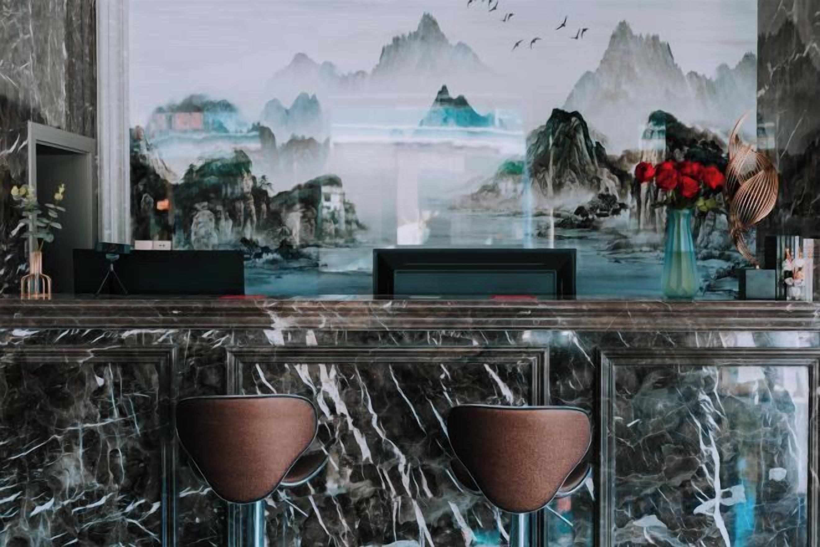 A bar area with a marble countertop, two bar stools, a television, and a decorative vase with flowers.