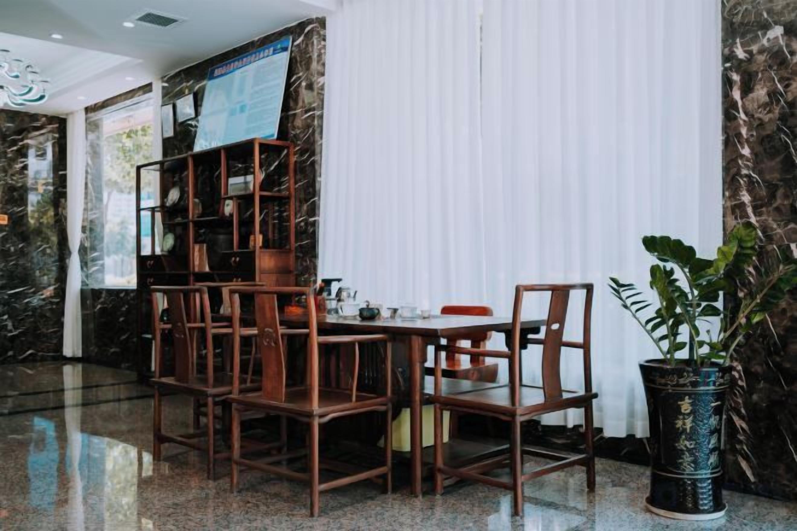 A dining area with a marble wall, a wooden bookshelf, and a potted plant.