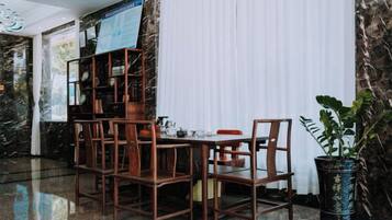 A dining area with a marble wall, a wooden bookshelf, and a potted plant.