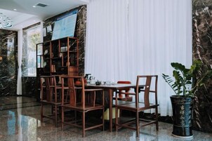 Espaço de refeições com parede de mármore, estante de madeira e planta em vaso.