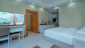 Une chambre d’hôtel moderne dotée d’un grand lit, d’un bureau avec une chaise, d’une télévision et d’une petite kitchenette.
