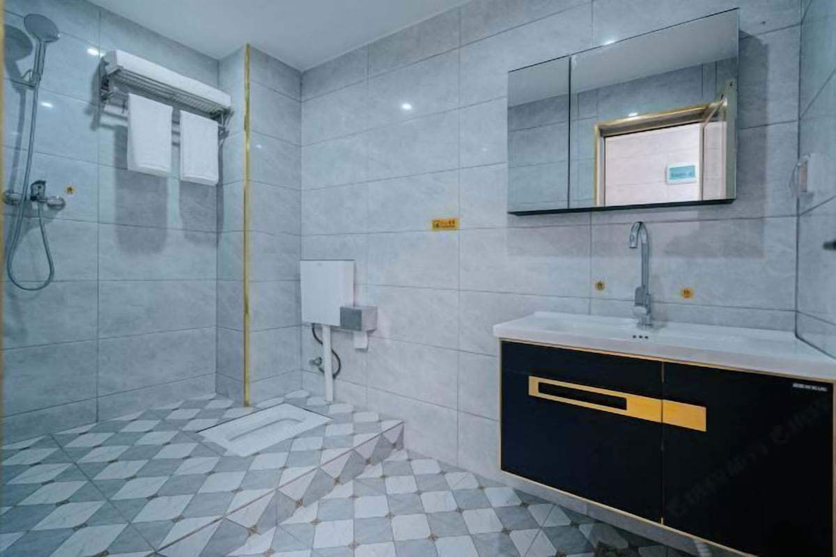 Un baño con ducha, lavamanos, espejo y suelo de baldosas.