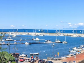 A marina with boats docked, a clear sky, and a distant mountain range.