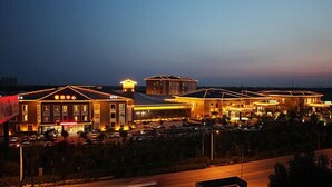 Un hotel con varias construcciones, estacionamiento y una entrada bien iluminada.