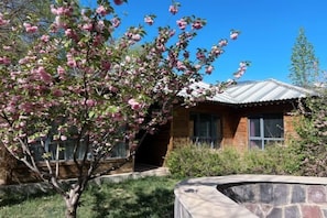 A house with a stone patio, a wooden deck, and a tree with pink blossoms. - Xiong'an Meiquan World Holiday hotel (Xiong County)