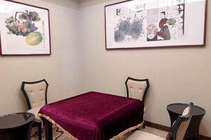 A room with a table and two chairs, a red table runner, and two framed artworks on the wall. - Xiong'an Meiquan World Holiday hotel (Xiong County)