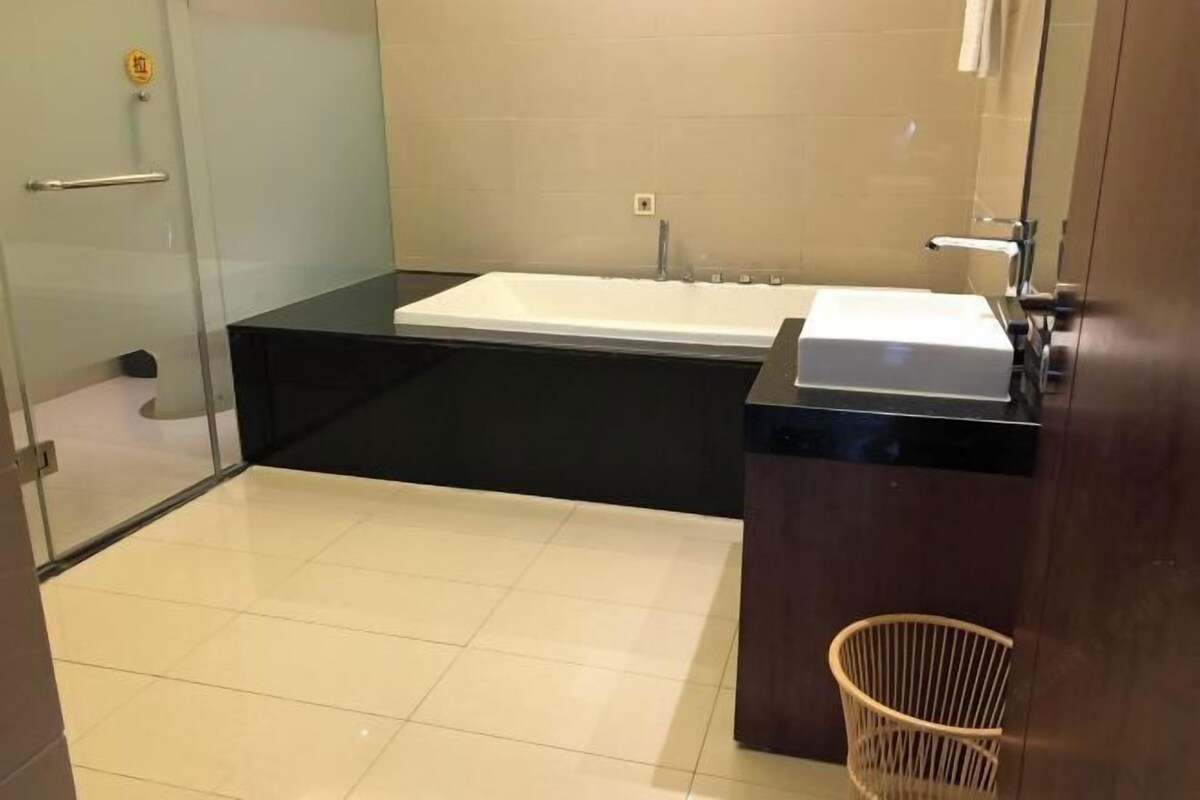 A modern bathroom with a large bathtub, a separate sink, and a glass shower enclosure.