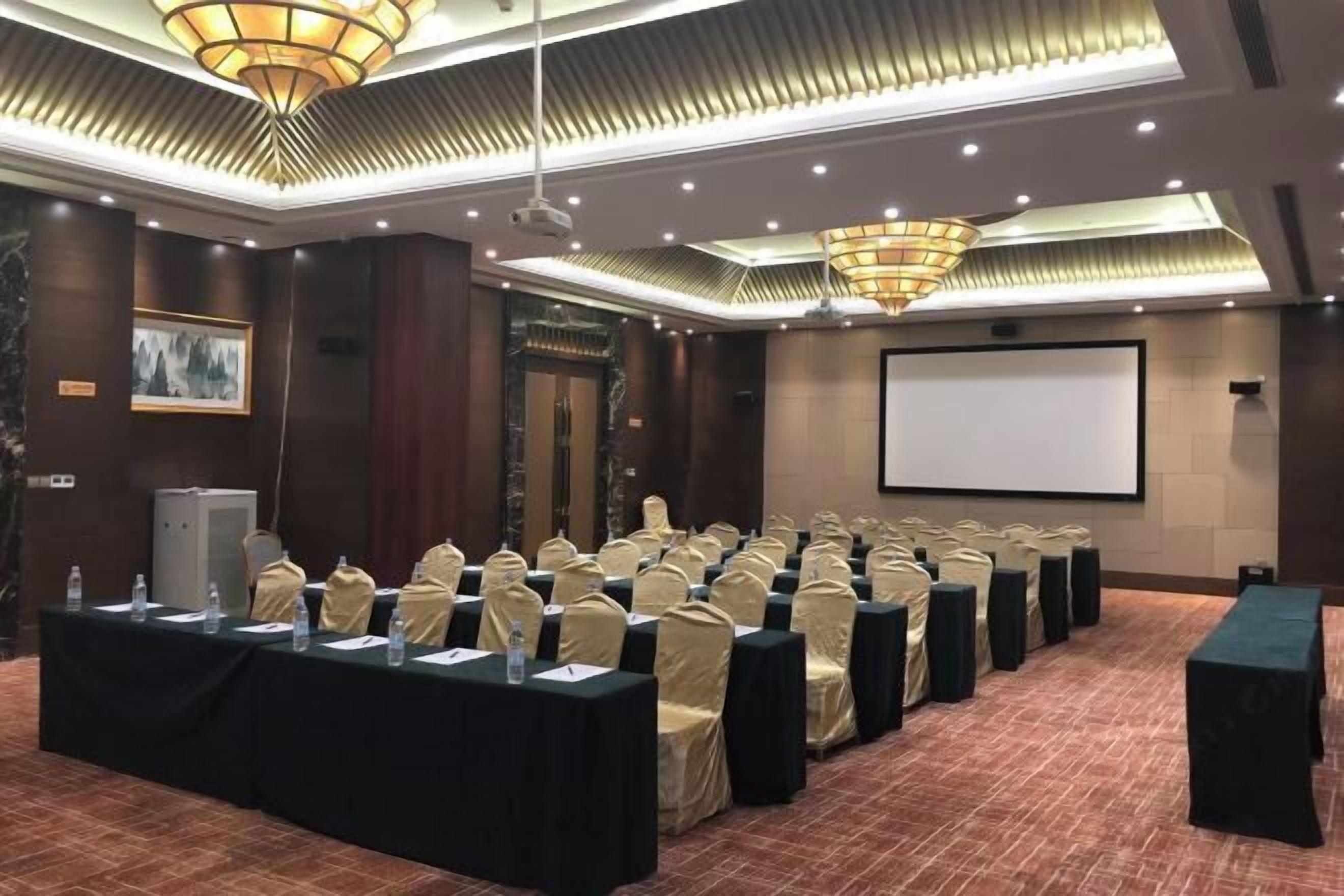 A conference room with rows of chairs, a projector screen, and a podium.