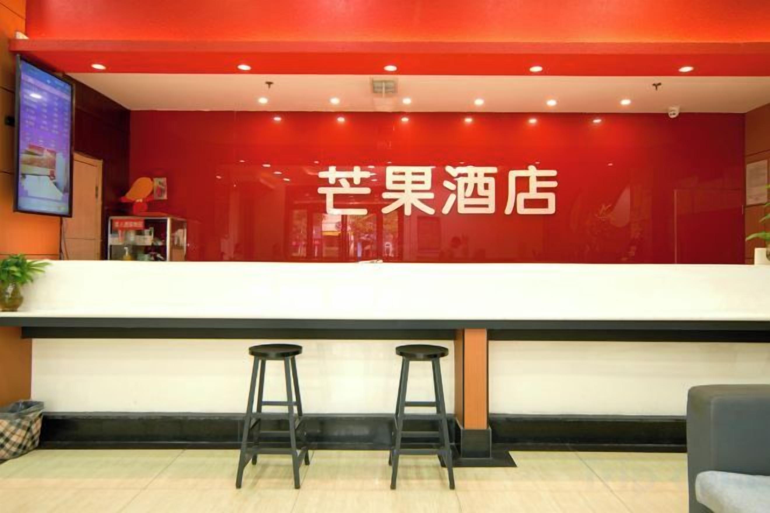 Un área de recepción con una pared roja y un mostrador blanco. Hay dos taburetes negros frente al mostrador.