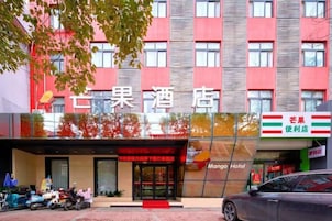 Un hotel con fachada roja, entrada visible y letrero que dice Mango Hotel.