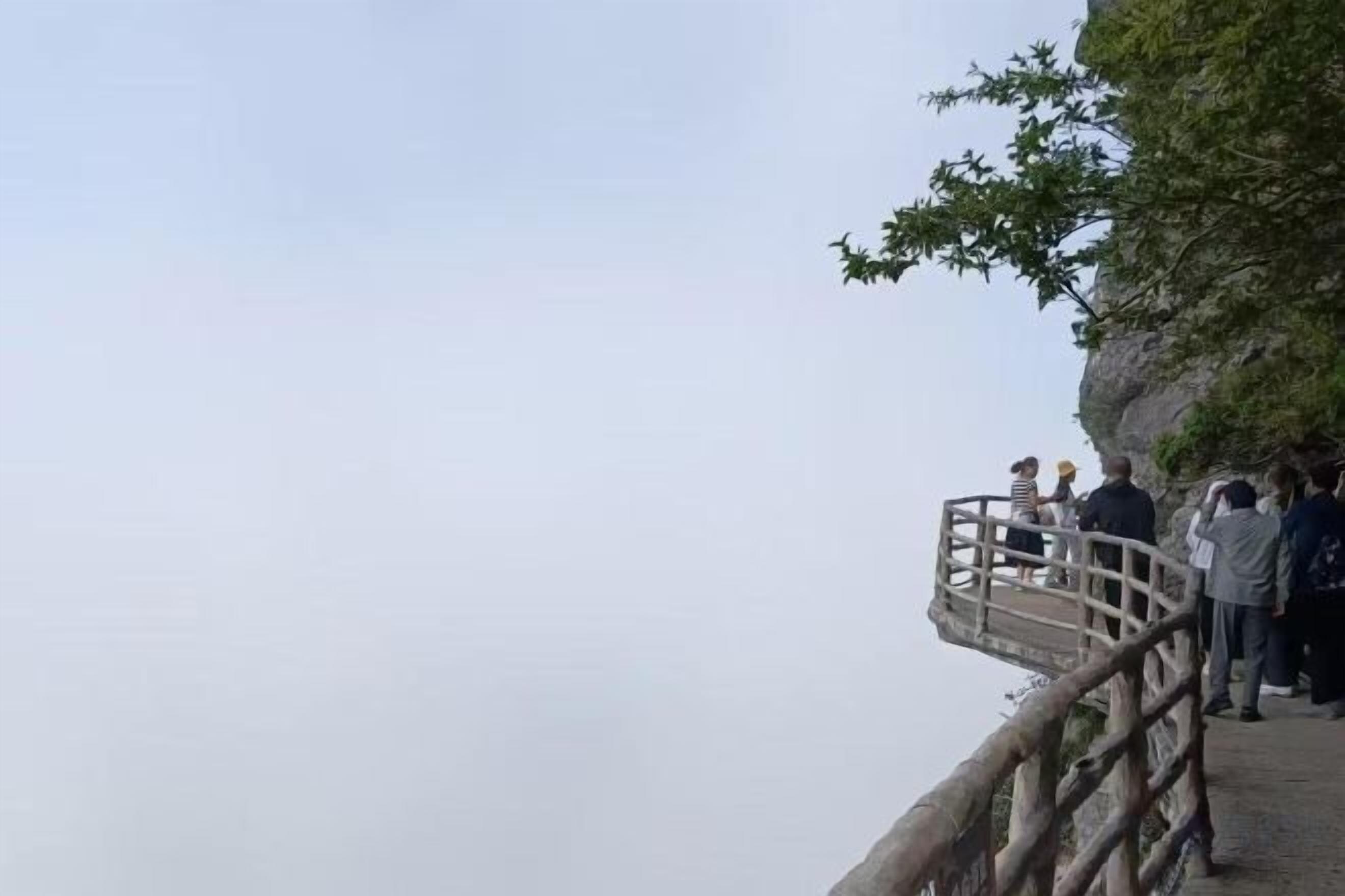 A wooden viewing platform with railings overlooking a cliff.