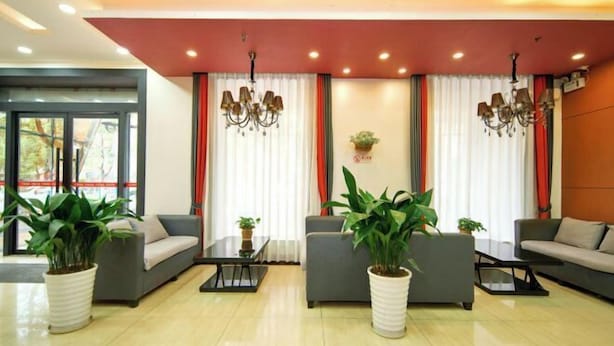 A modern lobby with grey sofas, a coffee table, and potted plants.