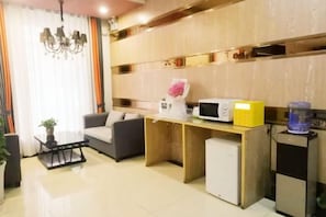 Una sala de estar moderna con un sofá, una mesita de centro, un microondas y un refrigerador pequeño.