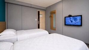 A hotel room with two beds, a television, and a mirror.