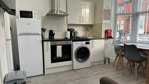 Une cuisine compacte équipée d’un four à micro-ondes, d’un four et d’un lave-linge. Un coin repas avec une table et des chaises est également à disposition.