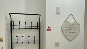Un porte-manteau en métal avec des crochets, un interrupteur fixé au mur, une prise de courant et un panneau en forme de cœur avec une citation sur l’amour.