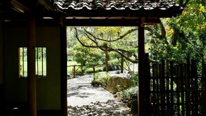 Ein traditioneller japanischer Garten mit einem Kiesweg, der durch ein hölzernes Tor führt.