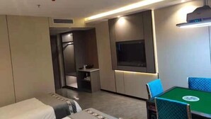 Ein Hotelzimmer mit einem Bett, einem Schreibtisch, einem Fernseher und einem Esstisch mit Stühlen.